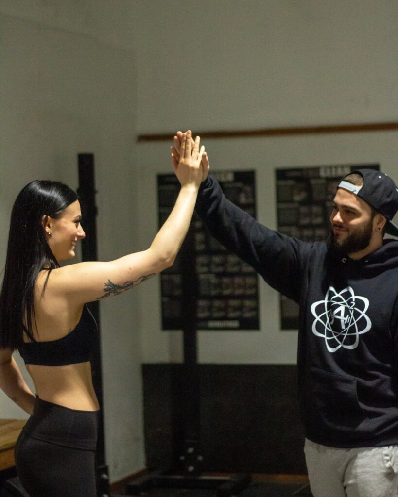 A happy fitness coach giving a high five to a female client during a private personal training workout session inside of one of Toronto's best gyms.